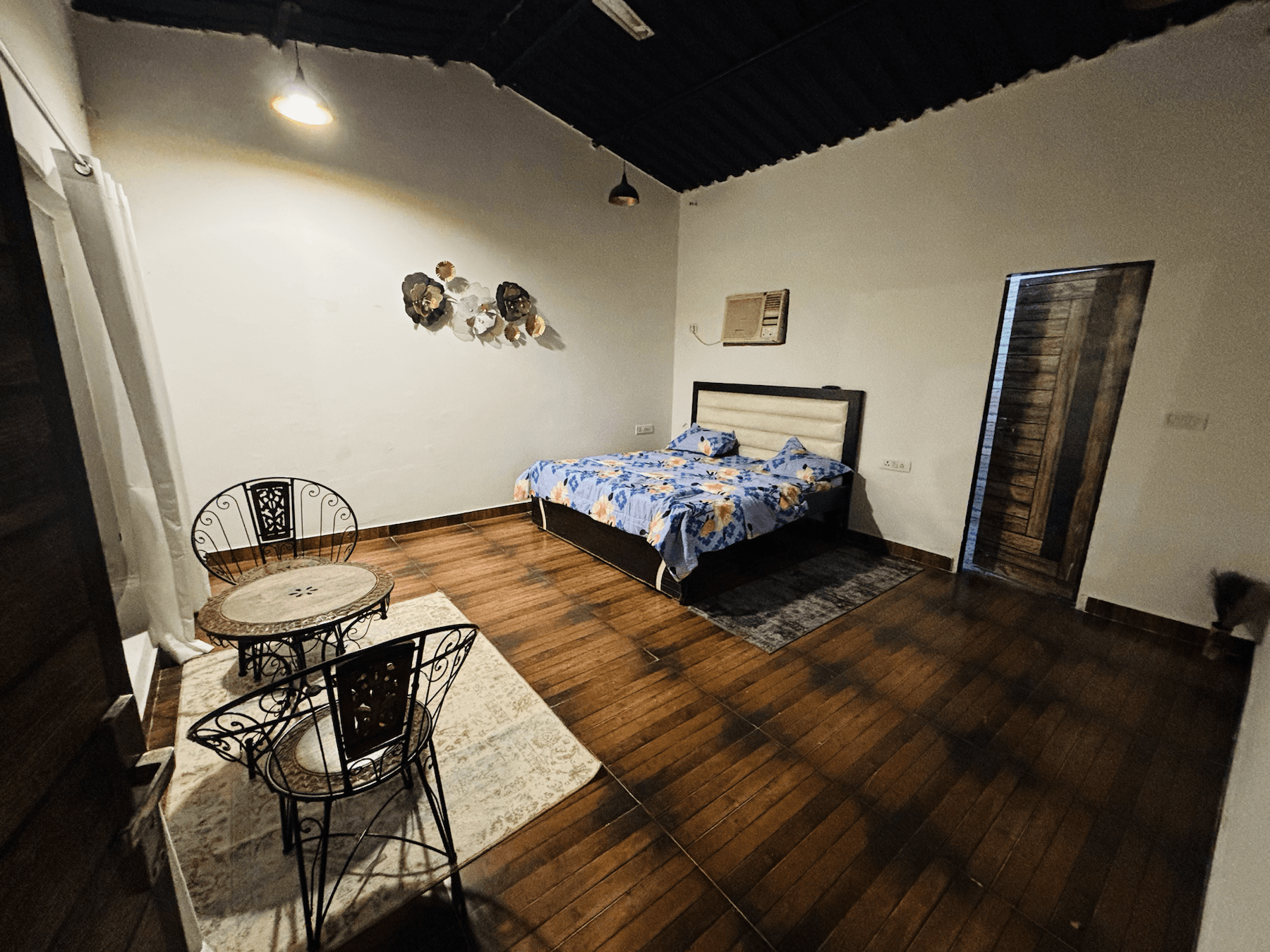 Spacious bedroom with wooden flooring and seating